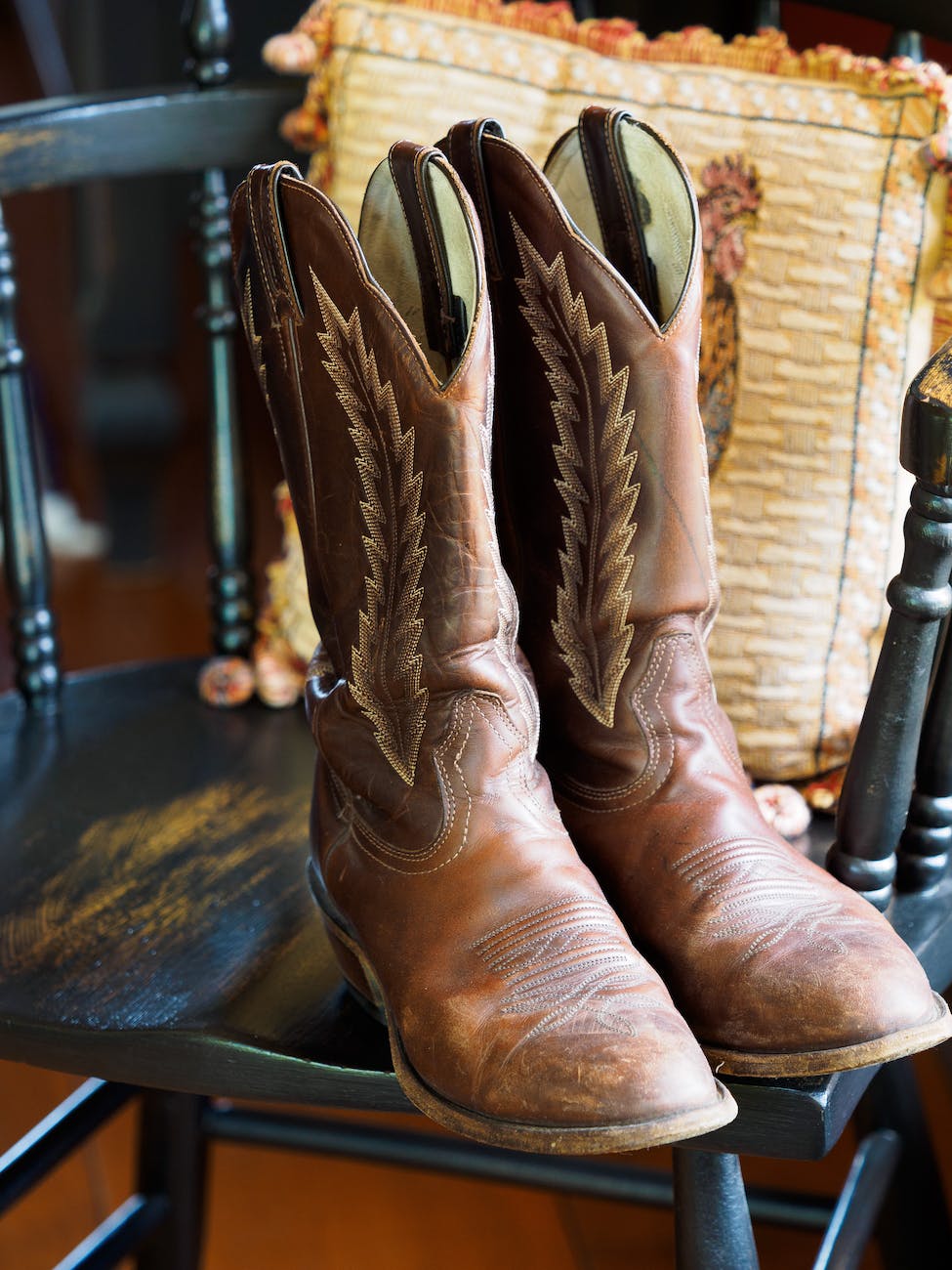 photo of a pair of cowboy shoes standing on a wooden chair