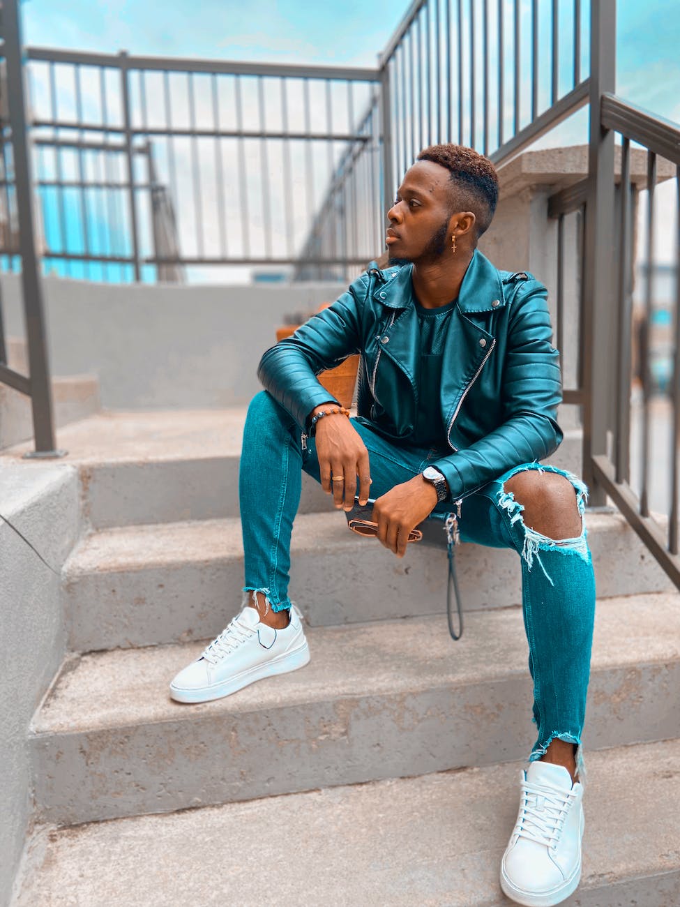 a man in blue leather jacket sitting on concrete stairs