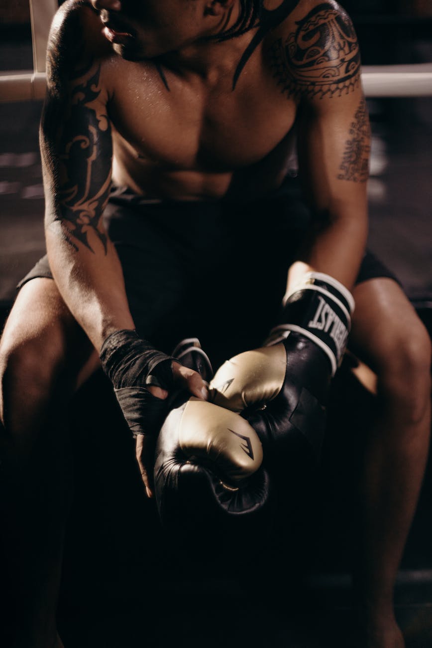 man in black tank top wearing blue and white boxing gloves