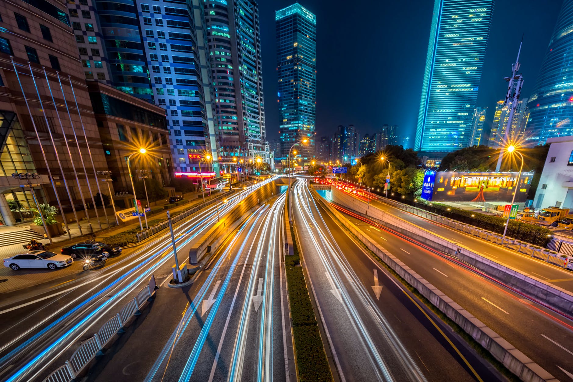 timelapse photography of vehicle on concrete road near in high rise building during nighttime