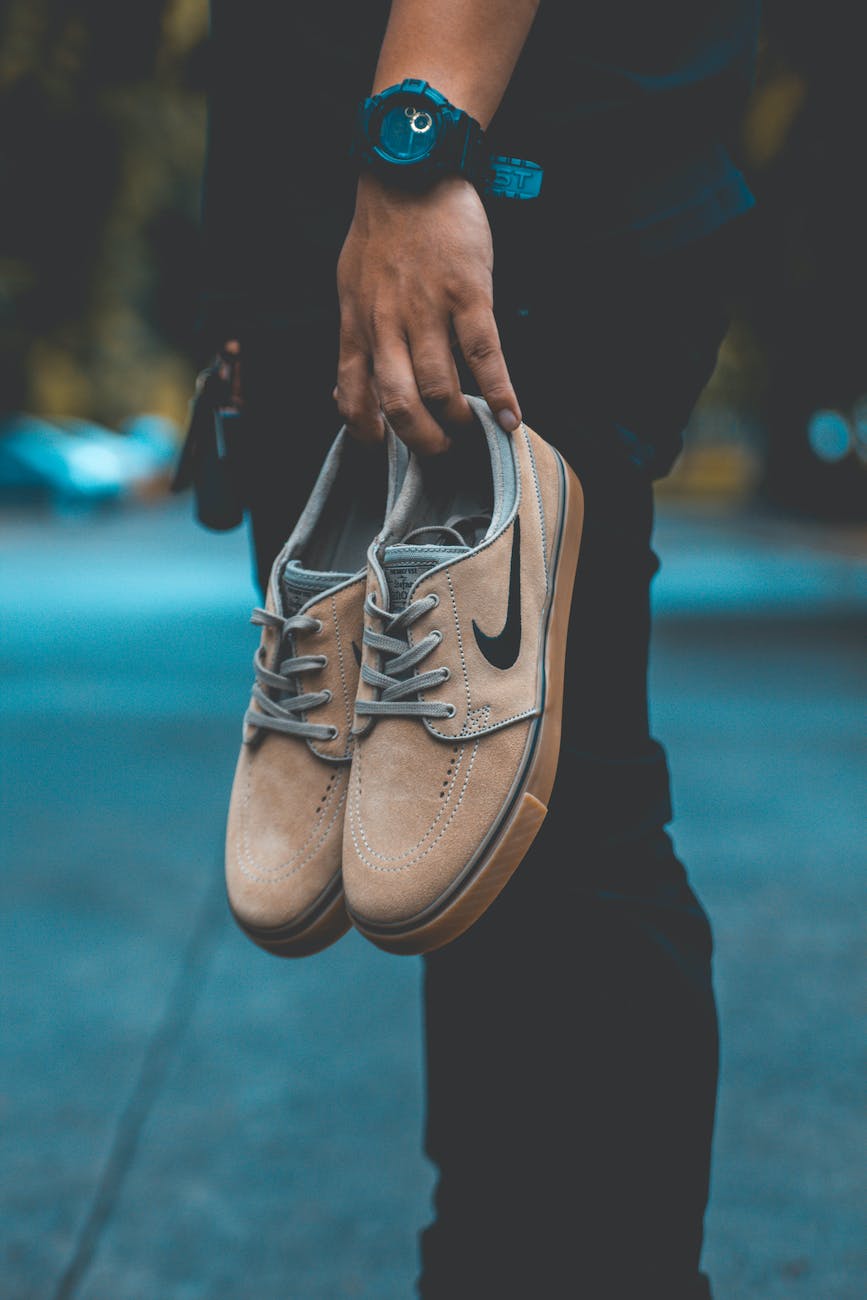 person holding pair of brown nike sneakers