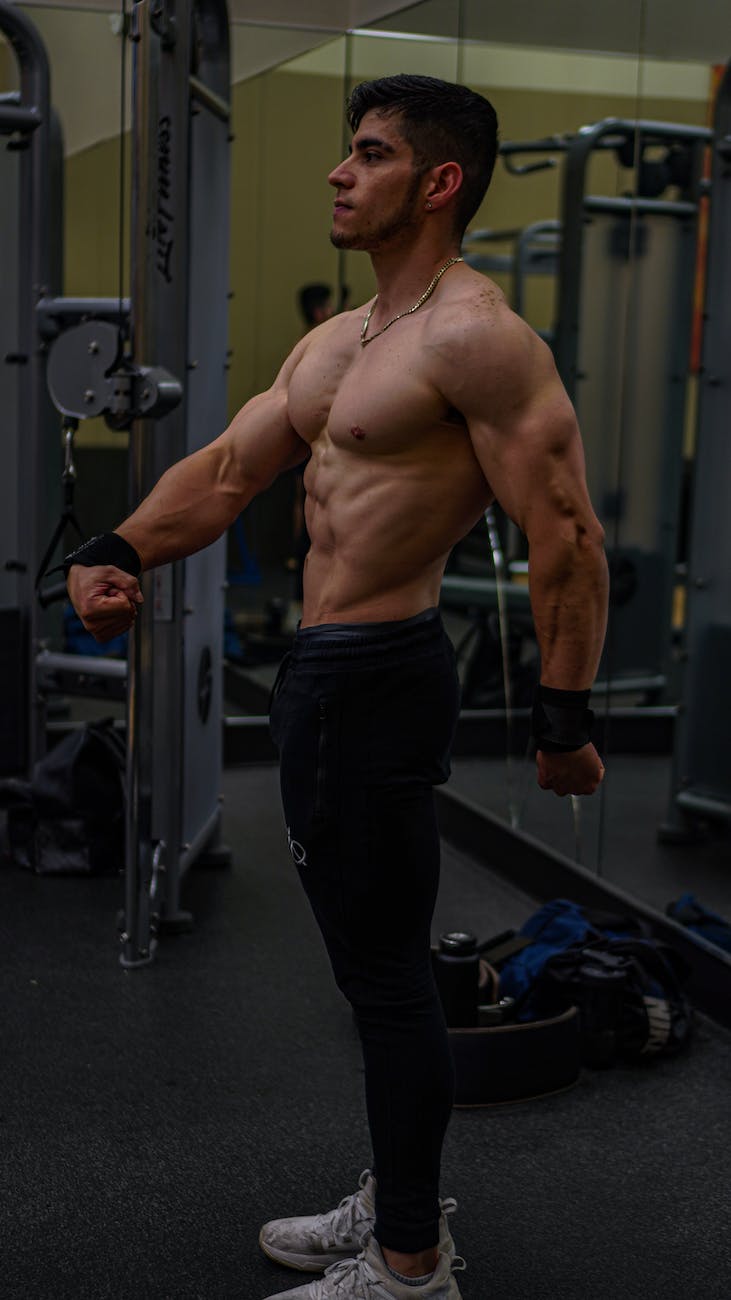 side view of a muscular man training in a gym