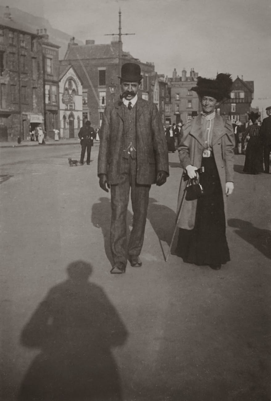 grayscale photo of man and woman walking on street