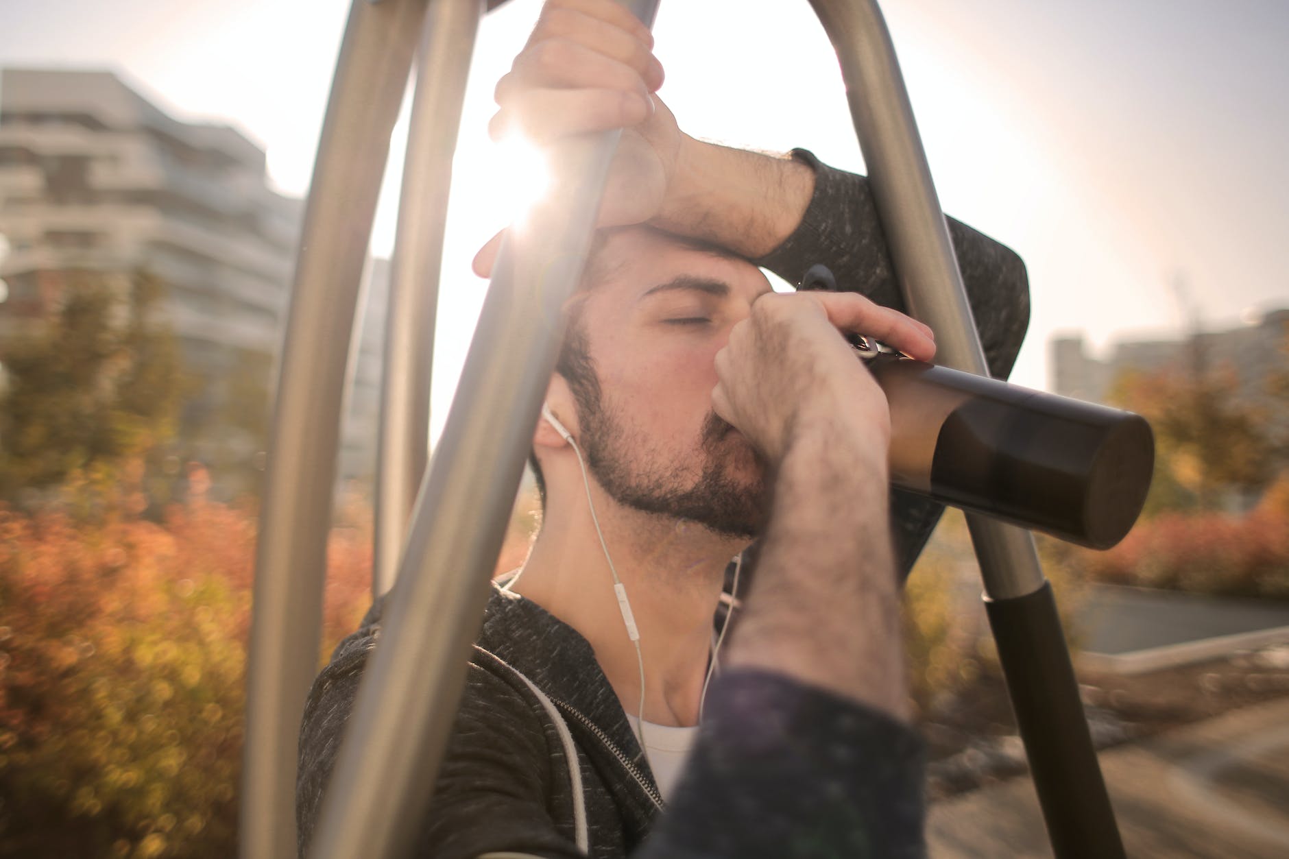 tired sportsman man drinking water during training on street