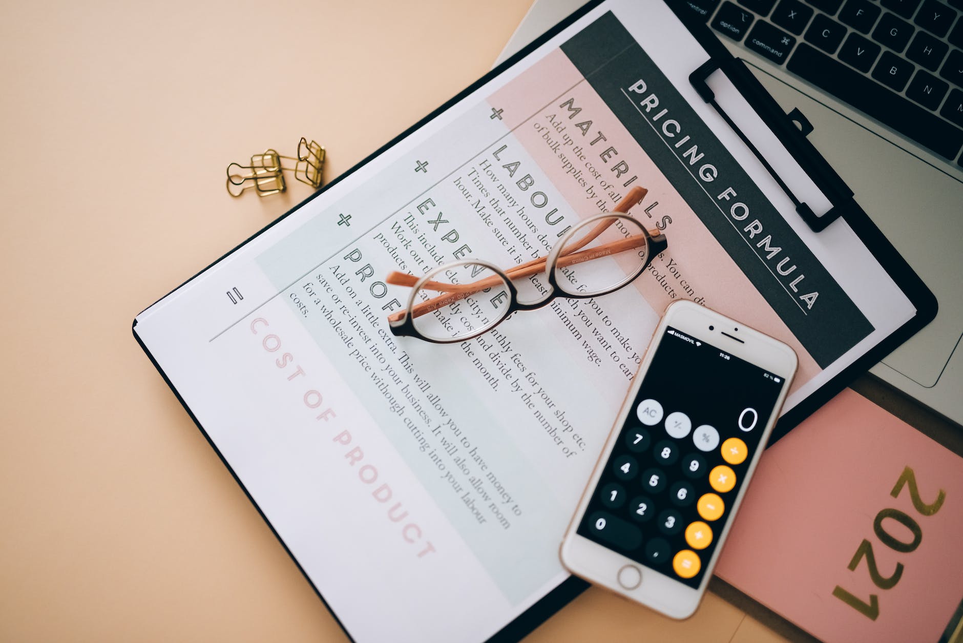 a phone calculator near the eyeglasses on clipboard with white paper