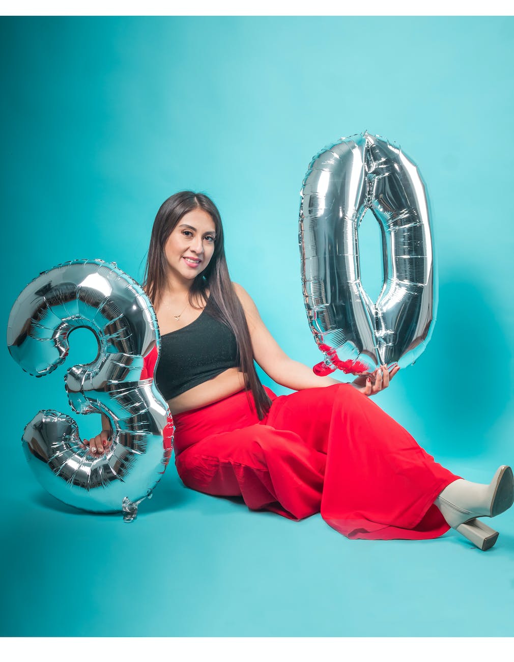 smiling woman sitting and posing with birthday balloons
