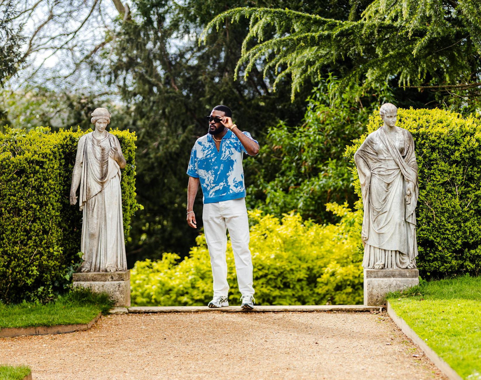 man in white pants posing in park