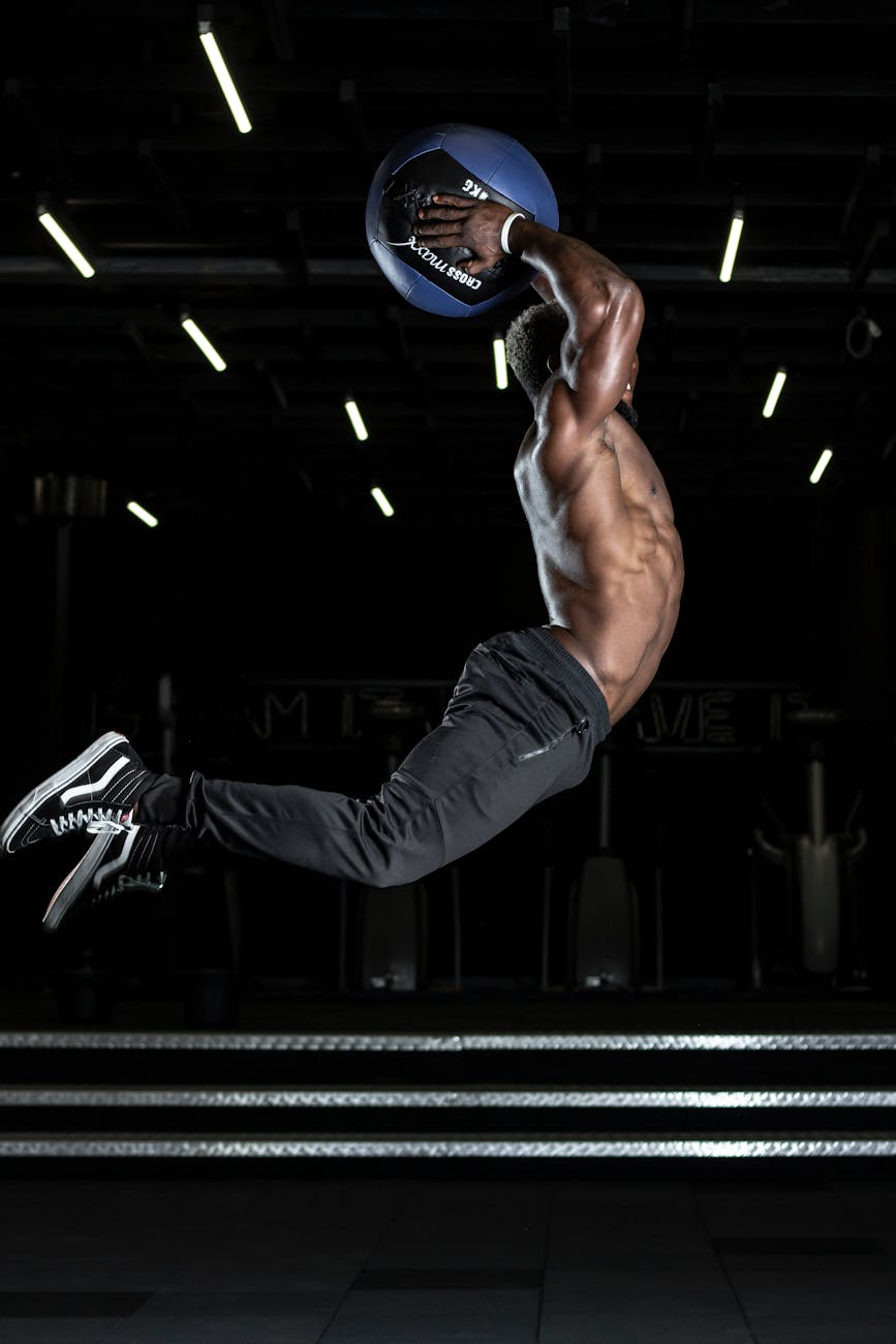 man jumping in mid air holding blue ball above his head